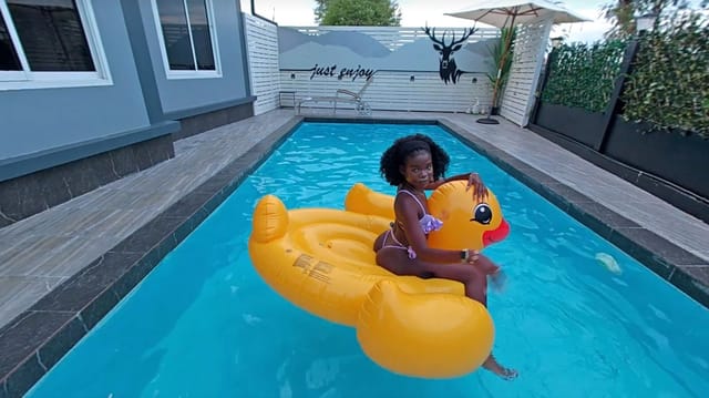 Amelia Star poses by the pool in a solo VR 4K POV video featuring ebony skin and wet body details.